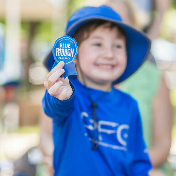A little boy holding a Blue Ribbon and smiling at the camera during Ice Cream Days in Le Mars.