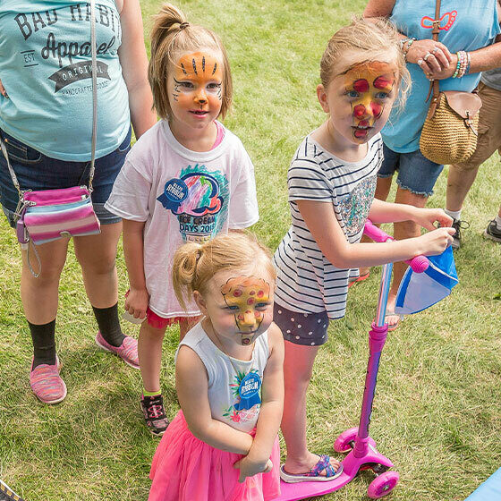 Three little girls with face paint smiling at the camera during ice cream days in le mars