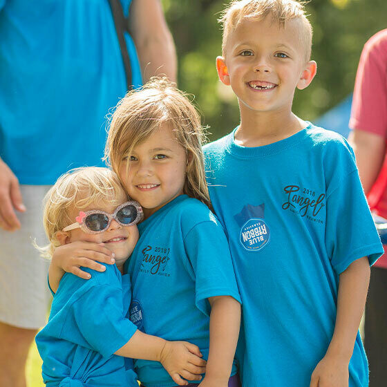 A little boy and his two younger sisters embracing and smiling at the camera during ice cream days in le mars.
