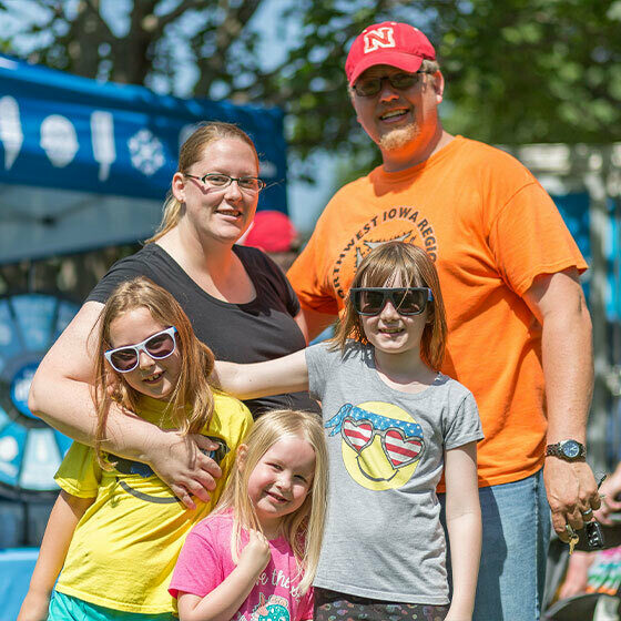 A mom and dad embracing their three young daughters and smiling at the camera during ice days in lemars.