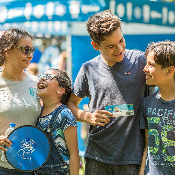 A mom, her older son, her younger son, and her daughter embracing and smiling during Ice cream days at le mars.