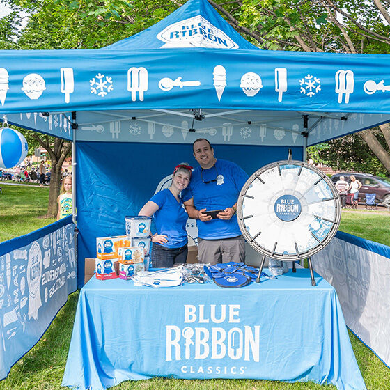 Two blue ribbon classics booth attendants smiling at the camera during ice cream days in le mars.