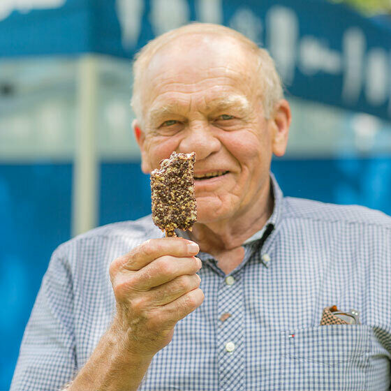 An elderly man holding up an ice cream and smiling at the camera during Ice Cream Days in Le Mars.